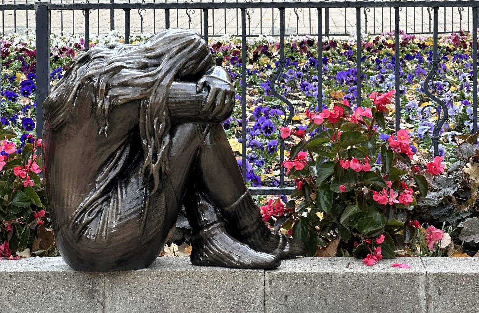 A NEM OKÉ kampány magányosan szomorkodó kislányt ábrázoló vándorszobra egy iskola kertjében