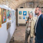 A Kortalanul Kreatív című kiállítás képeit szemléli két látogató.