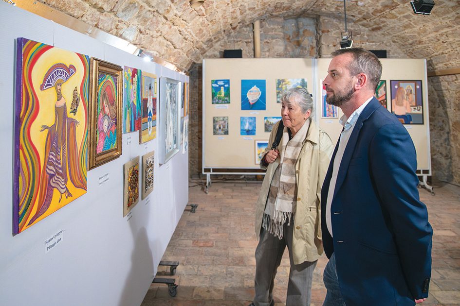 A Kortalanul Kreatív című kiállítás képeit szemléli két látogató.